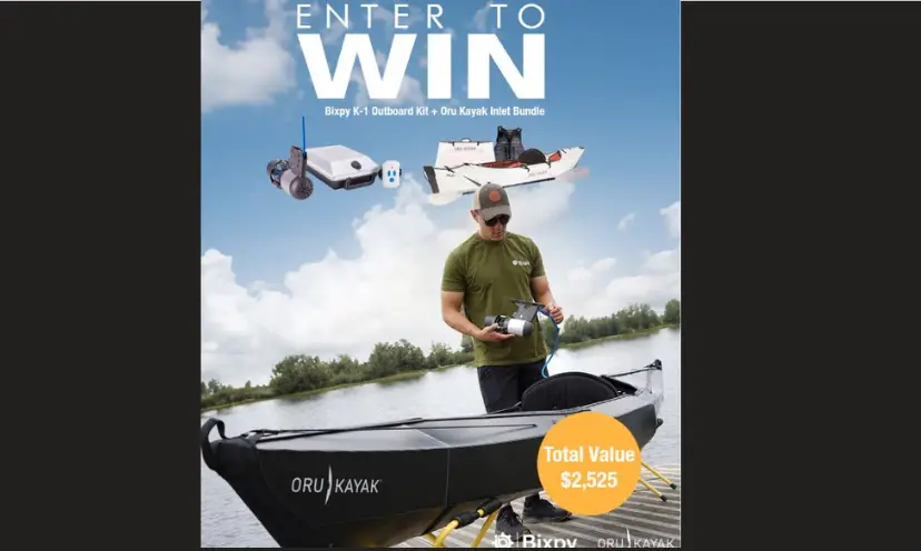 This photo features a man with a kayak and the motor and accessories in this giveaway. The kayak is at the edge of the water at a lake as if waiting for the adventure ahead!