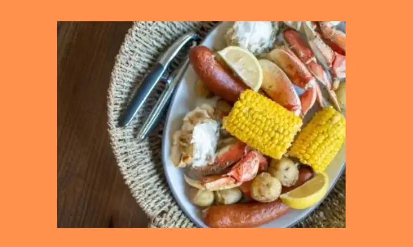 This photo has an orange background and features a plate filled every item that makes a luscious seafood boil and tasty feast from the ocean!