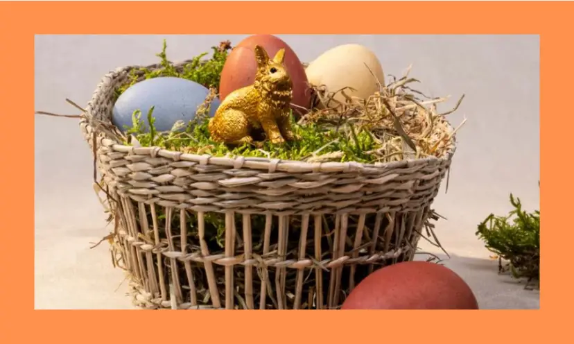 This is a photo of a beautiful straw basket filled with grass, straw, colored eggs and a Schleich bunny figure!