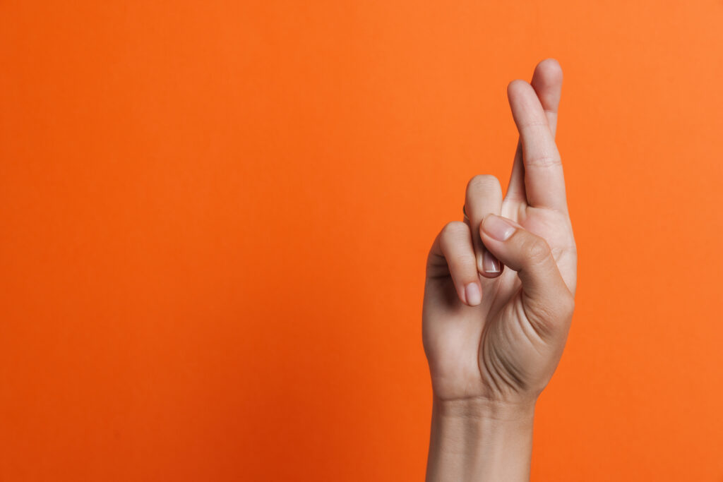the image shows a hand with it's fingers crossed
