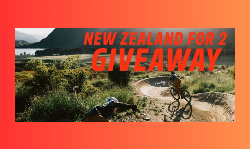 This is a photo of two people biking in the stunning terrain of New Zealand. In the distance of the trail is a stunning view of the water against the amazing mountains to make the ride one to remember!