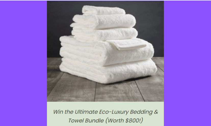 This photo features a stack of towels and linens like the ones the winner of this giveaway will receive. These are white, but the winner will choose the color they prefer. The text at the bottom says "win the ultimate eco-luxury bedding and towel bundle (worth $800!)