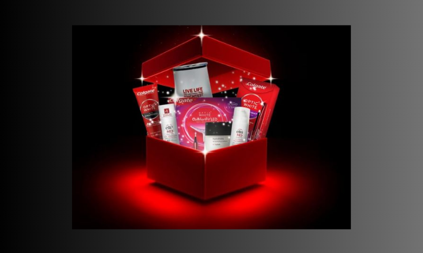 This is a photo of a very festive red box filled with items in the Colgate Obsessed Beauty bundle from this exciting giveaway! The background is black with the appearance of a red light shining from underneath the box.