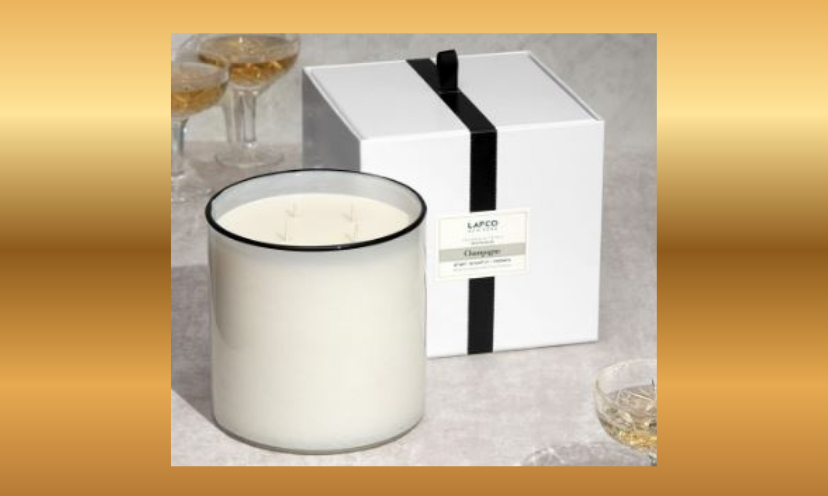 This is a photo of the $375 candle that you could win. It is featured beside it's special black ribbon gift box and a side of sparkling glasses of champagne!