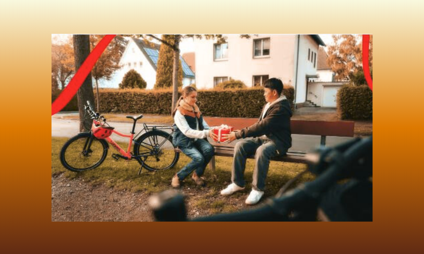 This is a photo of a young girl and boy exchanging a gift. They are outside, sitting on a park bench with their Woom bikes parked beside them!