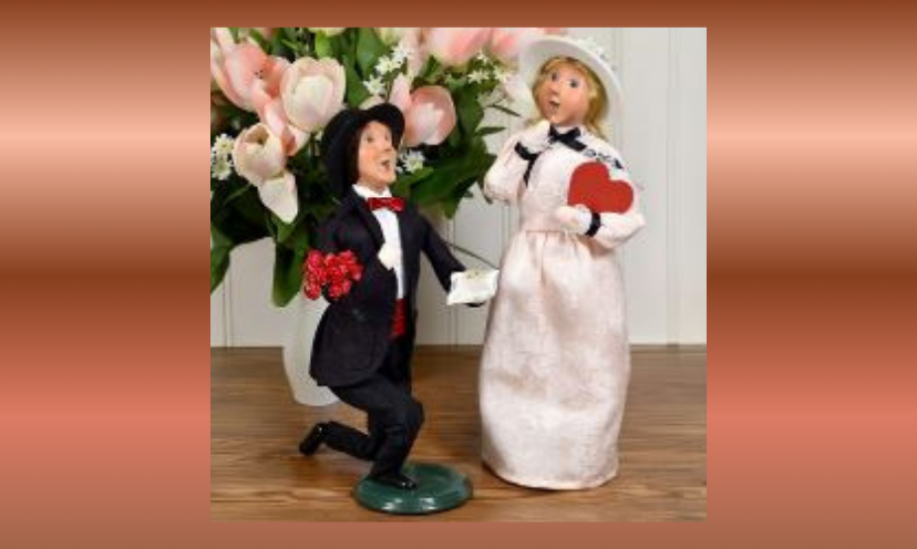 This is a photo of the Byers Choice figures offered in this giveaway. It is called "Season of Love" and the two piece set is that of a man on his knee, proposing to his lovely lady. He is holding flowers and the ring and she has a red heart clutched in her arm.