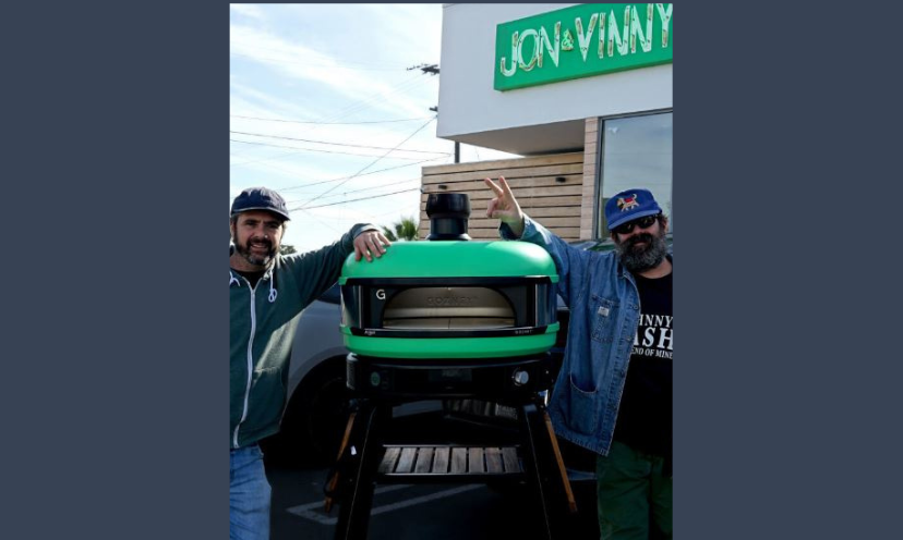 This is a photo featuring the hosts of this giveaway standing beside the Italian Gozney pizza oven grand prize!