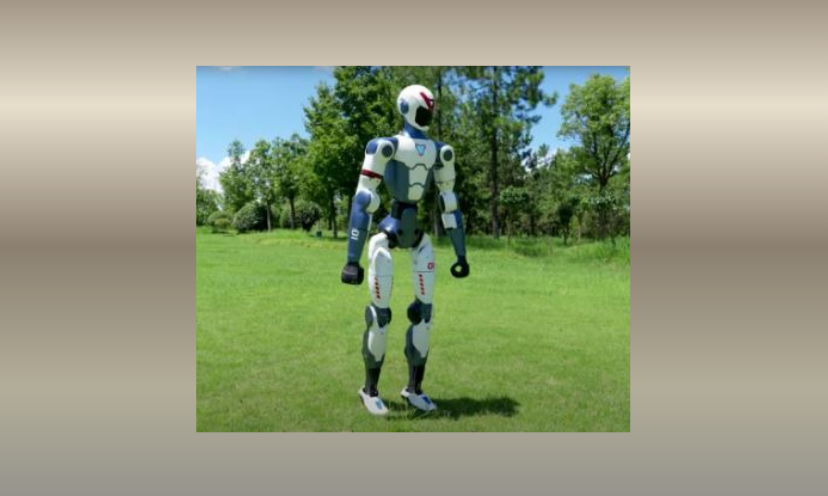 This photo features a full length image of the Unitree R1 Humanoid Robot that you could win in this giveaway! The robot is shown standing in a green grass space with a backdrop of green trees!